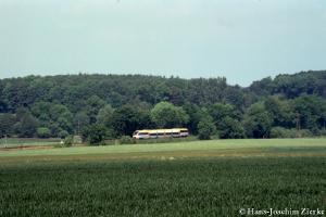 Yellow-white DMU in the middle of green fields and 
forests.